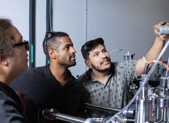 Three students adjusting experimental equipment.