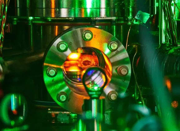 A shiny metal vacuum chamber with red light emanating from inside.