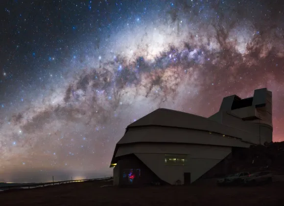 A ground view of an observatory with the Milky Way galaxy in the background.
