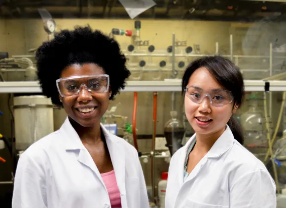 Researchers posing for a portrait in lab by a fume hood