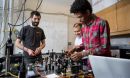 Three researchers stand around a work bench covered in research equipment