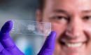 A graduate student displays a microscope slide holding an array of more than 300 microparticles