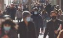 People walking on a city sidewalk wearing masks during the coronavirus epidemic.