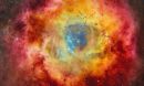 Stars on a dark blue background surrounded by clouds of a yellow, red and magenta nebula.