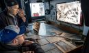 three polar scientists studying an image on a computer screen