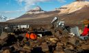 The photo shows a scientist adjusting equipment in Antarctica.