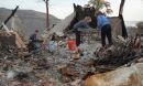 Two women sorting items on a table amongst piles of debris.