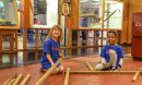 Two kids sitting on the floor in a science center building a wooden structure.