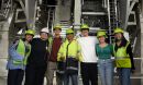 Group photo of students and mentors wearing hard hats in front of interior workings of the Inouye Solar Telescope facility