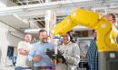 A professor instructing students on how to use a robot.