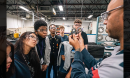 Closeup of tour guide demonstrating gas flow control system to students in safety glasses