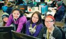 Four smiling kids behind computers.