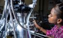 A student turns a knob on a large piece of metal equipment.