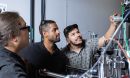Three students adjusting experimental equipment.