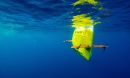 Underwater image of a bright yellow autonomous underwater vehicle in royal blue water.