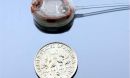 implantable infusion micropump next to a dime for size comparison