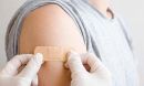 doctor putting adhesive bandage on young man's arm