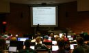 students in an auditorium looking projector screen