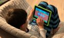 little boy sitting on a sofa playing with a tablet