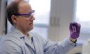 professor Andrew Whelton holds up a water sample from a building faucet