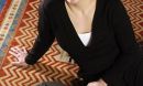 woman seated on rug next to blue, circular device labeled Roomba