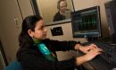 Photo of researcher and a colleague in a sound booth using a computer to record sound