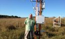 Scientist standing next to cosmic-ray soil moisture sensor