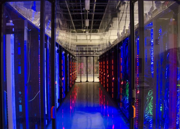 A dark hallway flanked by glowing walls of computers