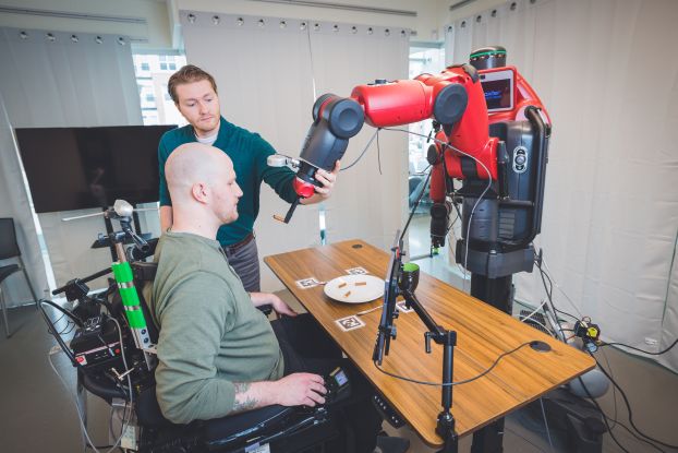 a person controls a robot to feed himself