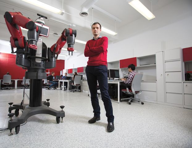A man stands in a lab next to a large robot