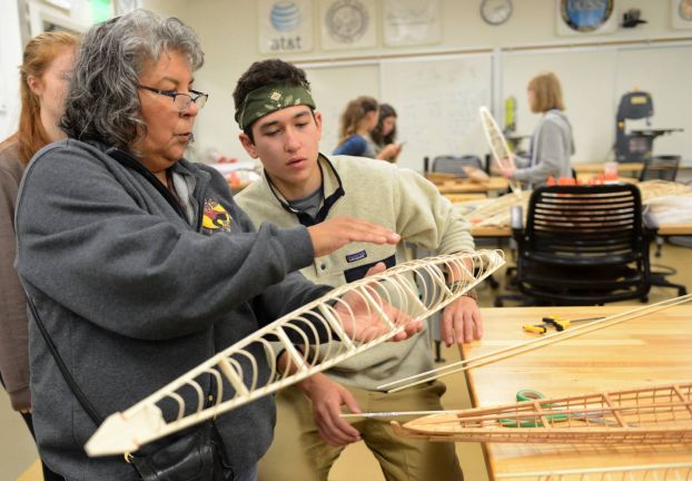 A teacher and student working on a kayak keel.