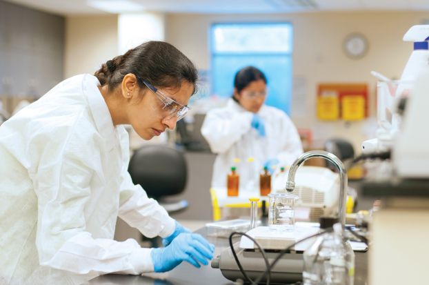 A student in a laboratory wearing a lab coat and goggles.