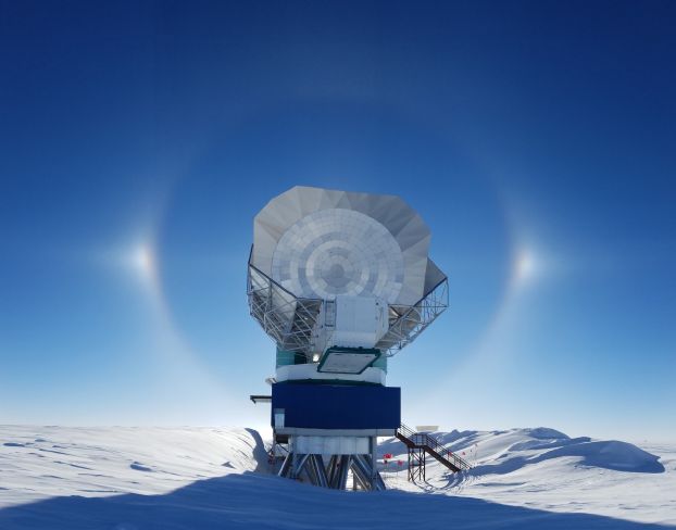 A large telescope surrounded by snow-covered, barren scenery.