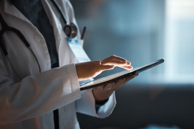 A close-up of a doctor holding a touchscreen.