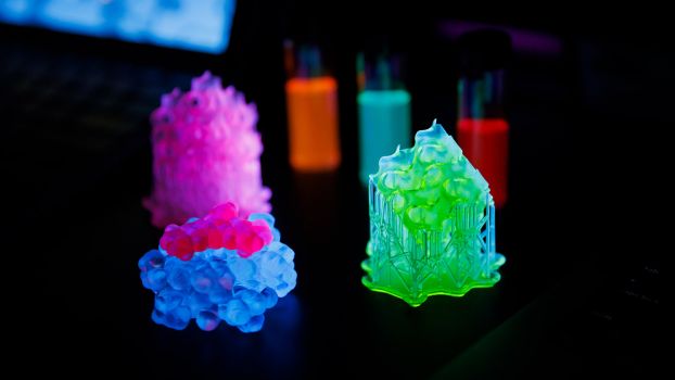 Brightly colored glowing 3D-printed objects on a black background.