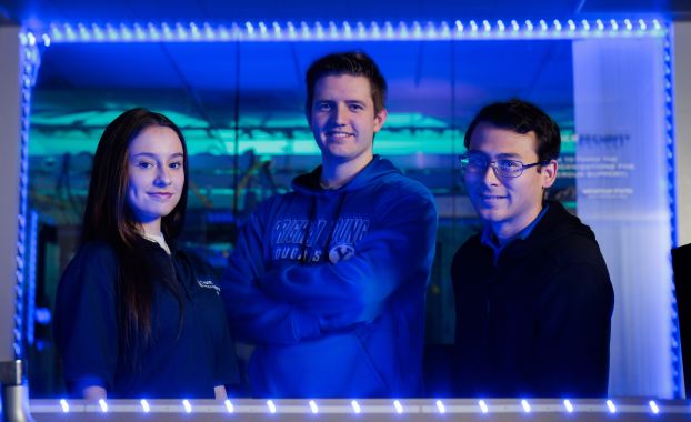 Three college students smiling at the camera.
