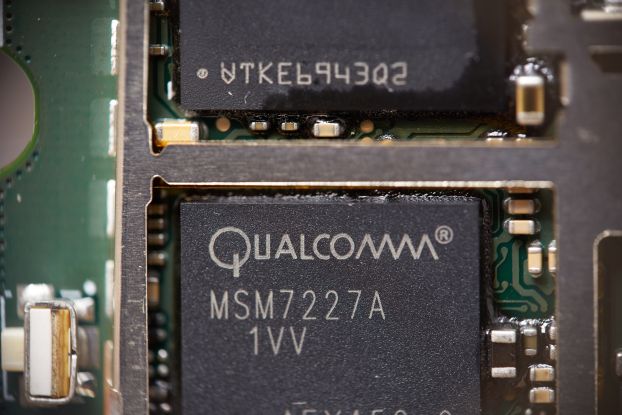 A close-up of a circuit board containing a dark box labeled 'Qualcomm.'
