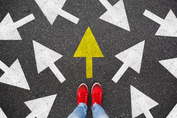 Feet standing on pavement with painted arrows.