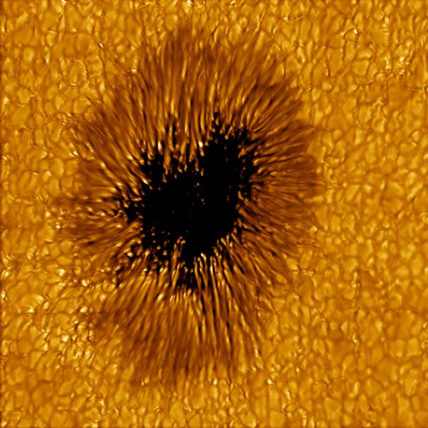 A crackly orange surface with jagged spikes surrounding a dark spot.