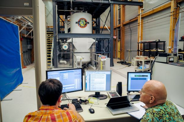 Researchers sitting at computers with a large research MRI unit in the background.