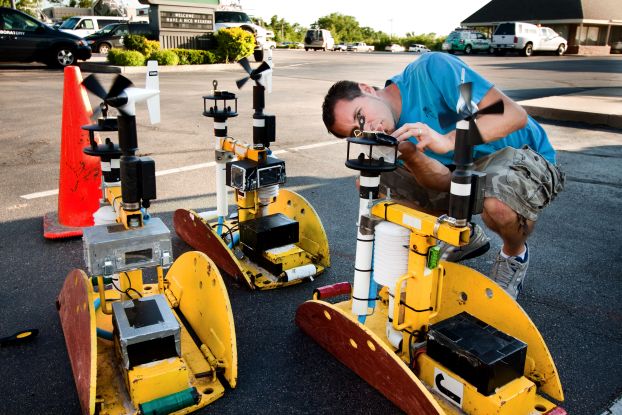 A researcher handles a large piece of scientific equipment in a parking lot.
