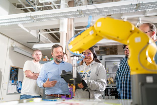 A professor instructing students on how to use a robot.