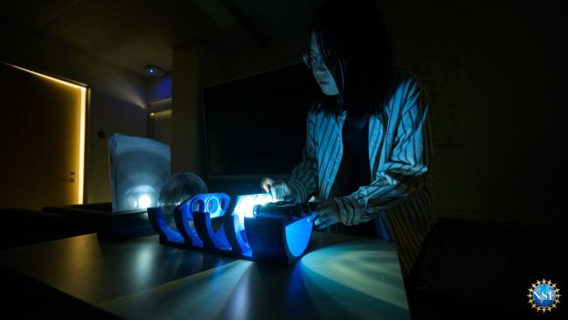 A research assistant adjusts OptiDot, a 3D-printed optical device.
