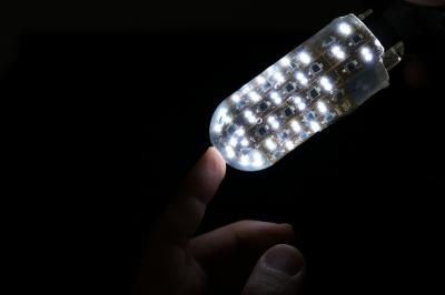 Robotic finger with no synthetic skin over it, revealing lights underneath, touching human finger