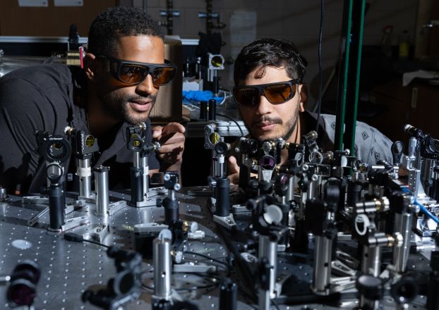 Two researchers working with lasers on a table.