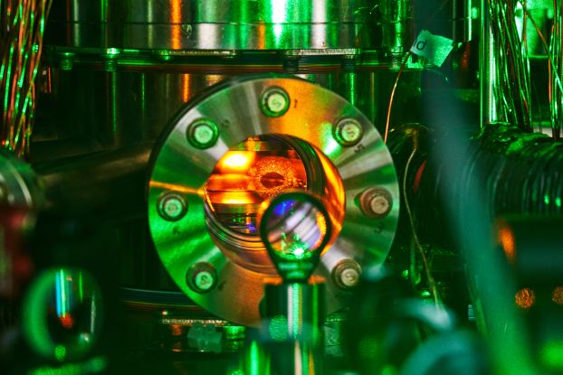A shiny metal vacuum chamber with red light emanating from inside.