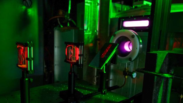 A laser table in a dark lab with red laser light visible and optical equipment.