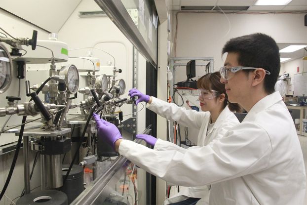 Researchers testing chemistry equipment in a fume hood.