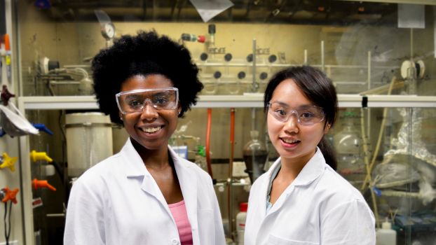 Researchers posing for a portrait in lab by a fume hood