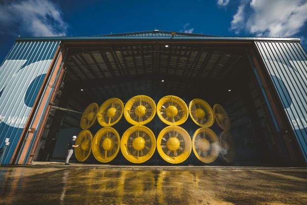 Twelve giant yellow fans inside a large warehouse.
